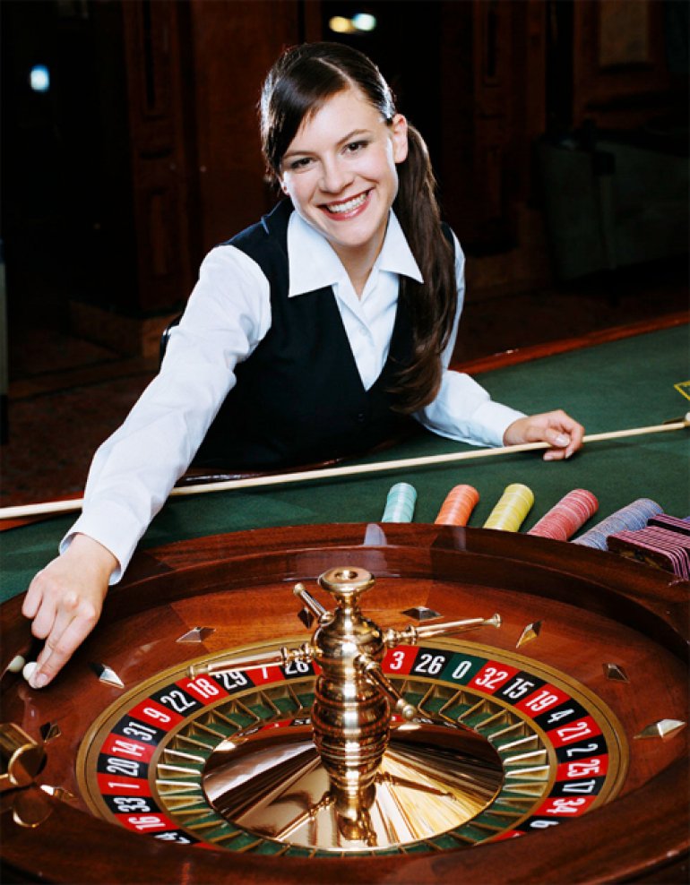  Ragazza carina che sorride al croupier, gestisce la pallina su una roulette 